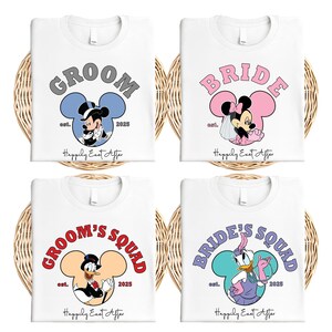 Può includere: Quattro magliette bianche con disegni di personaggi Disney per un matrimonio. Le magliette presentano Topolino e Minnie, e Paperino e Paperina. Il testo include "Groom", "Bride", "Groom's Squad" e "Bride's Squad", con "est. 2025" e "Happily Ever After".