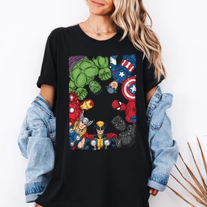 A woman wearing a black t-shirt with a graphic of various Marvel superheroes, including Hulk, Captain America, Spider-Man, and others, standing against a white background.