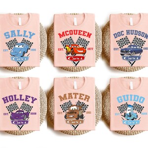 a set of four pink bibs with cars on them