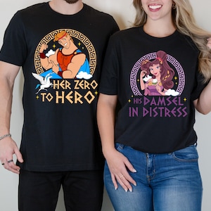 May include: Two black t-shirts with a graphic print of characters from the Disney movie Hercules. The shirt on the left has a graphic of Hercules with the text "Her Zero to Hero". The shirt on the right has a graphic of Megara with the text "His Damsel in Distress".
