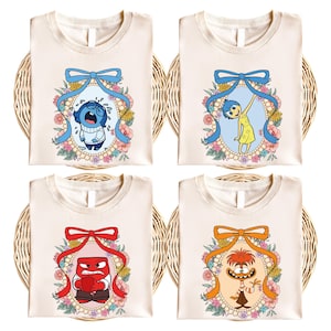 May include: Four white t-shirts with different characters from the movie Inside Out. Each character is surrounded by a floral wreath and a blue bow. The characters are Sadness, Joy, Anger, and Disgust.