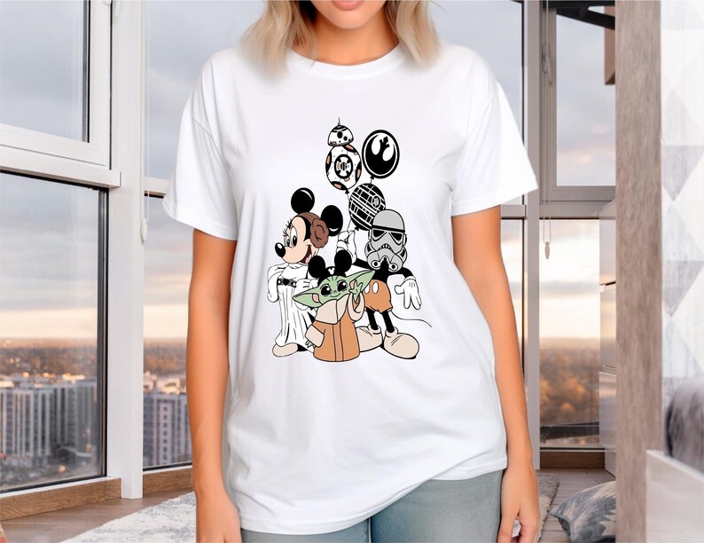 May include: White t-shirt with a graphic print of Mickey Mouse, Yoda, and a Stormtrooper from Star Wars. The characters are holding balloons with the Star Wars logo and the Death Star.
