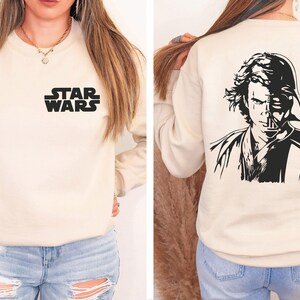 a woman wearing a star wars sweatshirt and ripped jeans