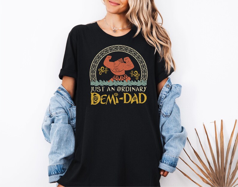 May include: Black t-shirt with a vintage-style graphic of a cartoon character with the text "Just an Ordinary Demi-Dad".