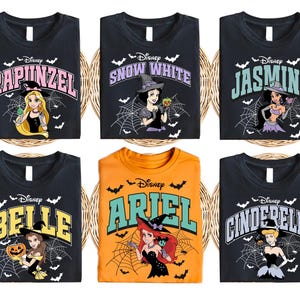 May include: Six black t-shirts with different Disney princess characters in a Halloween theme. The shirts feature the princesses dressed in witch costumes with bats and spiderwebs in the background. The text on the shirts reads "Disney" and the name of the princess. The princesses featured are Rapunzel, Snow White, Jasmine, Belle, Ariel, and Cinderella.