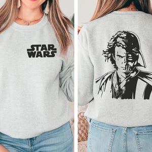 a woman wearing a star wars sweatshirt and jeans