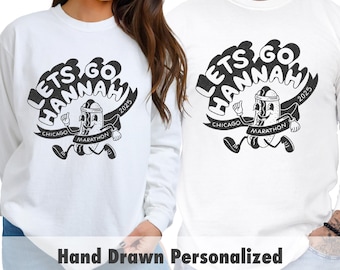 May include: Two white crew neck t-shirts with a black and white graphic design of a hot dog running with the text "Let's Go Hannah Chicago Marathon 2025".