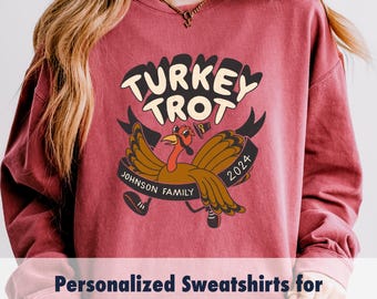 May include: A red sweatshirt featuring a graphic of a running turkey with the text "TURKEY TROT" and "JOHNSON FAMILY" on a banner. The year 2024 is also included in the design.