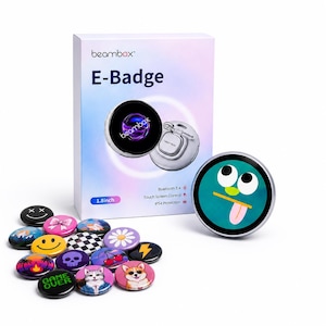 Könnte beinhalten: Eine weiße Schachtel mit dem Text "beambox E-Badge" neben einem silbernen und schwarzen kreisförmigen Gerät und einer Sammlung bunter Ansteckbuttons. Das Gerät hat einen Durchmesser von etwa 4,5 cm. Die Knöpfe haben verschiedene Designs.