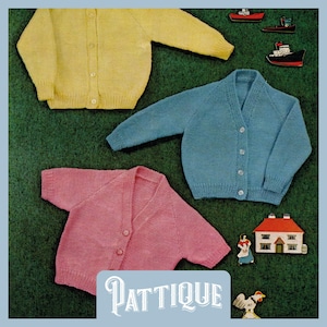 Könnte beinhalten: Drei Strickjacken in verschiedenen Farben: Gelb, Blau und Rosa. Die Jacken haben einen V-Ausschnitt und einen Knopfverschluss. Die Jacken liegen auf einer grünen Oberfläche.