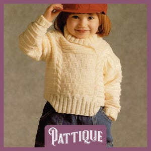 May include: A white knitted jumper with a cable knit pattern and a turtleneck collar. The jumper is worn by a child wearing a red baseball cap and blue jeans. The image includes the text "PATTIQUE".