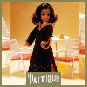 Peut inclure: Une robe en tricot marron avec des bordures dorées et un col en V. La robe est portée par une poupée aux cheveux bruns et aux yeux bleus. La poupée est debout devant une table et des chaises blanches. Le texte "PATTIQUE" est imprimé en bas de l'image.