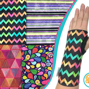 May include: A black wrist support with a vibrant zigzag design is displayed on an arm. The image also shows fabric samples with diverse patterns, including stripes, triangles, and paisley motifs. The wrist support has a thumb hole and a small label.
