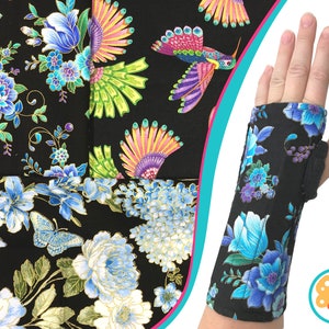 May include: Black fabric with blue and white floral patterns, including peonies and butterflies. A wrist brace with the same floral design is shown. The brace has a black, padded interior and a butterfly logo.