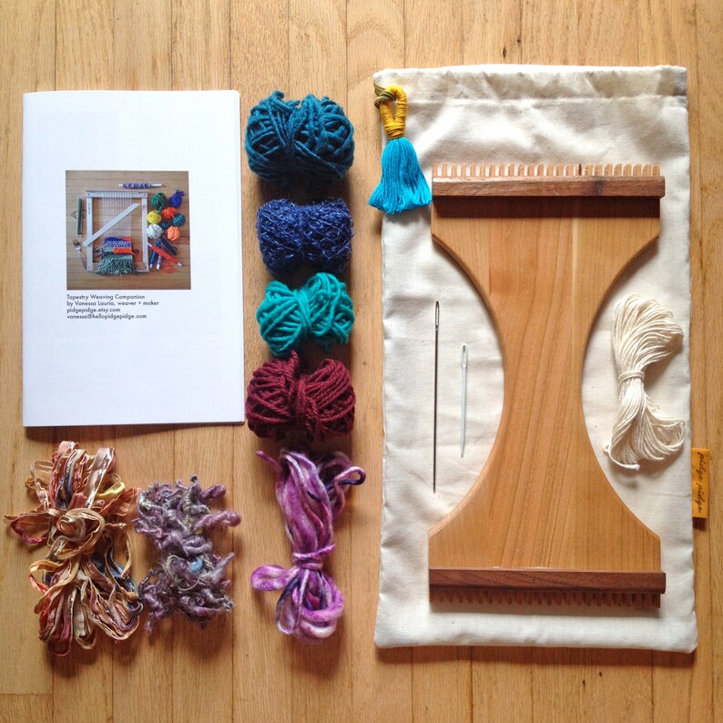 May include: A weaving kit with a wooden loom, yarn in teal, blue, green, and burgundy, and a canvas bag. The kit includes a booklet, needles, and decorative yarn bundles. The loom is approximately 12 inches wide.