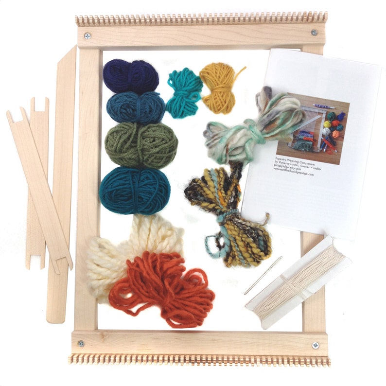 May include: A wooden tapestry weaving loom kit with various colored yarn balls, weaving tools, and instructions. The yarn colors include navy, teal, olive green, yellow, cream, and rust. The loom is rectangular and has a natural wood finish.
