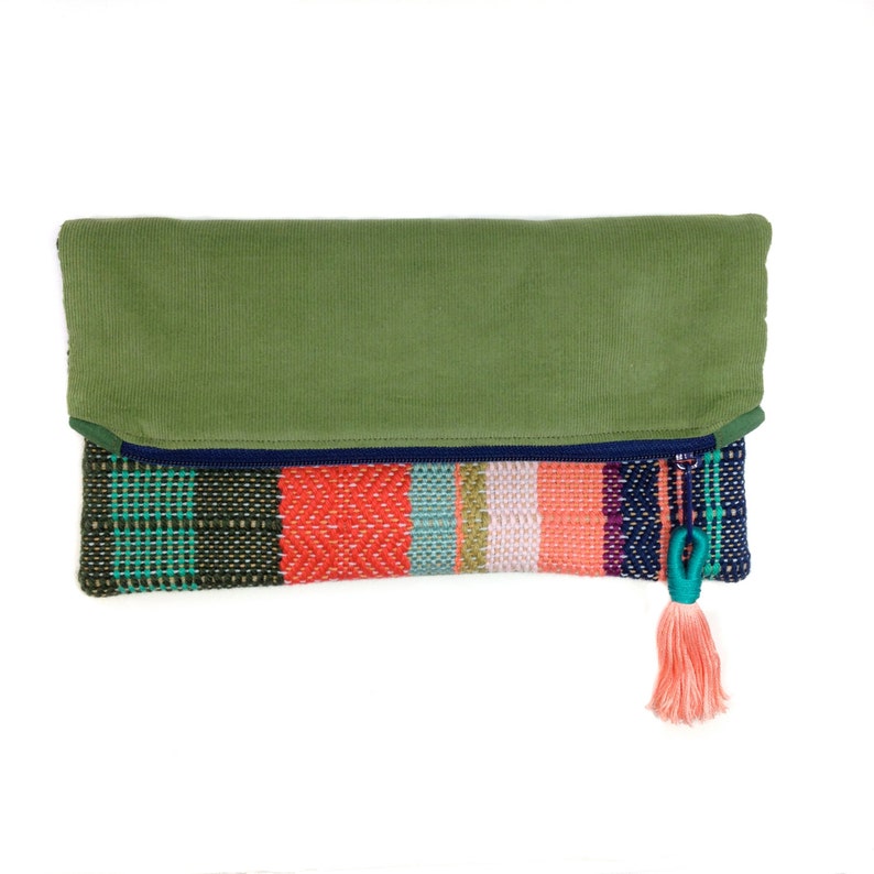 Peut inclure: Une pochette color&eacute;e avec un rabat en velours c&ocirc;tel&eacute; vert olive. Le corps tiss&eacute; pr&eacute;sente des rayures turquoise, rouges, roses et bleu marine. Un pompon corail est suspendu &agrave; une boucle turquoise, ajoutant une touche d&eacute;corative.