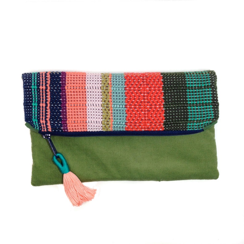 Peut inclure: Une pochette verte avec un rabat tiss&eacute; color&eacute;. Le rabat pr&eacute;sente des rayures marine, corail, blanc, sarcelle et rouge. Une tirette de fermeture &eacute;clair bleu marine avec une boucle sarcelle et un pompon p&ecirc;che compl&egrave;tent le design.