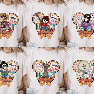 May include: White t-shirts featuring colorful Disney-themed graphics with characters from the movie "Coco." Each design includes a character illustration, a name, and the phrase "Un Poco Loco" on a banner. The graphics are set within a Mickey Mouse head shape.