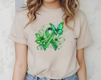 May include: Beige t-shirt featuring a green ribbon with the words "Cerebral Palsy Awareness", a green butterfly, and green floral accents. The design is centered on the front of the shirt.
