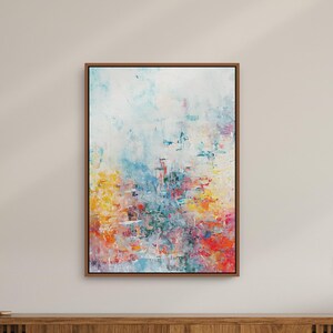 Può includere: Dipinto astratto con sfondo bianco e pennellate colorate in tonalità di blu, giallo, rosso e rosa. Il dipinto è incorniciato in una cornice di legno marrone.