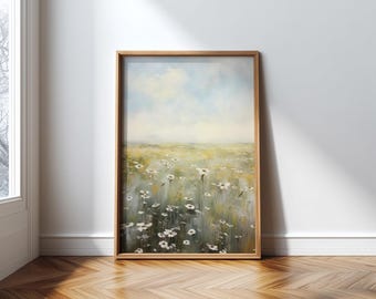 May include: A framed artwork depicts a field of white flowers under a soft blue sky. The painting has a light, airy feel with a wooden frame. The artwork is displayed against a white wall and rests on a wooden floor.