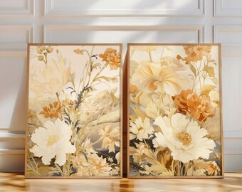 May include: Two framed floral art prints. The prints feature a watercolor style with large, creamy white and orange flowers. The artwork has a soft, warm color palette with a light beige background and wooden frames. The prints are displayed on a wooden floor.