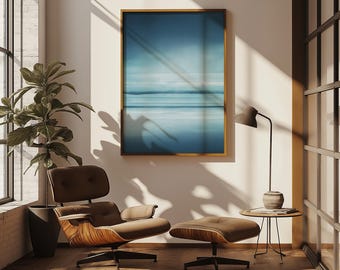 May include: A modern living room scene featuring a brown lounge chair with a matching ottoman, a framed blue abstract art piece, and a black floor lamp. A potted plant sits near a large window, and a small side table holds a decorative vase.