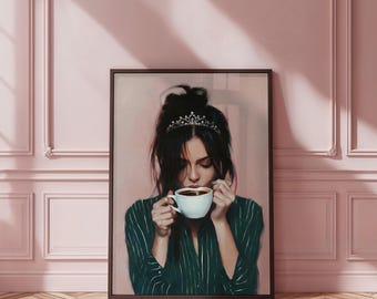 May include: A framed art print depicts a woman with dark hair wearing a tiara, sipping coffee from a white cup. She is dressed in a green striped shirt. The background is a soft pink, and the artwork is framed in a dark brown frame.