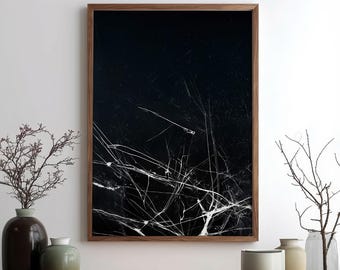 May include: Abstract art print in a dark wooden frame. The artwork features a black background with white, linear patterns resembling cracks or veins. The print is displayed on a wooden surface with decorative vases.