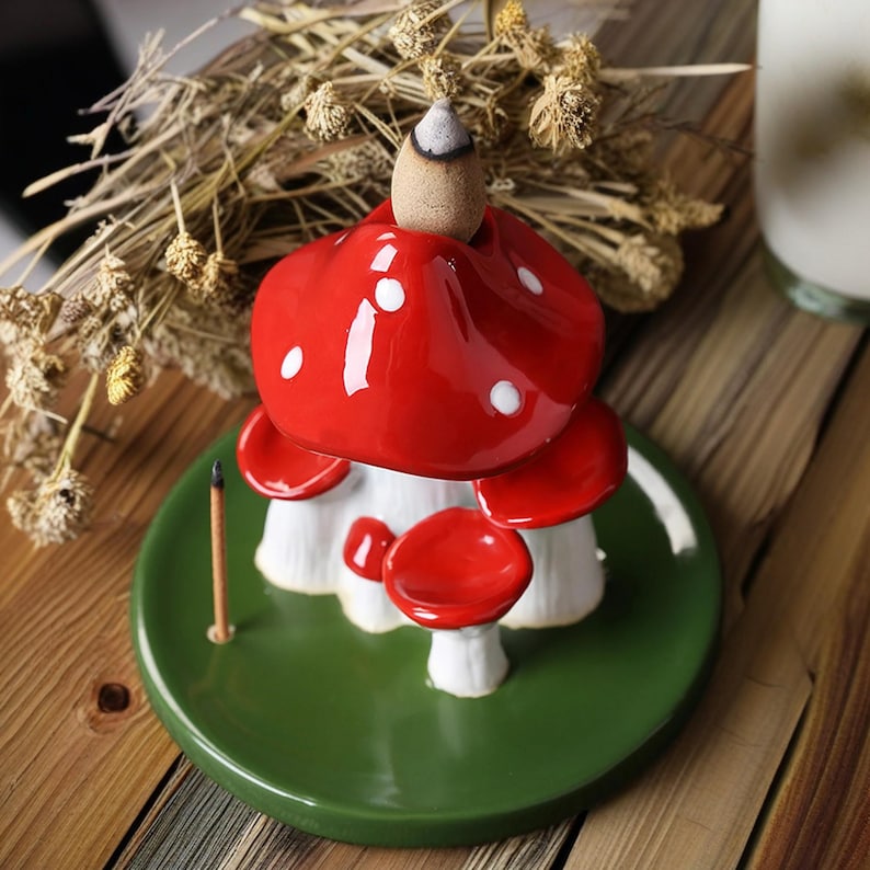 K&ouml;nnte beinhalten: Ein roter und wei&szlig;er Keramik-R&auml;ucherofen in Pilzform mit gr&uuml;nem Sockel. Der R&auml;ucherofen ist f&uuml;r einen konischen R&auml;ucherst&auml;bchen konzipiert.