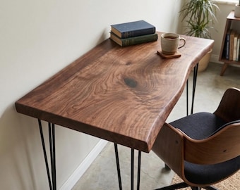 May include: A wooden desk with a live edge and black hairpin legs. The desk has a natural wood grain finish. Two books and a mug on a coaster sit on the desk. A wooden and black chair is next to the desk.