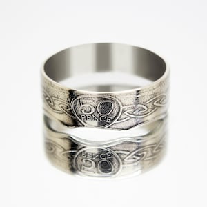 Peut inclure: Une bague en argent fabriquée à partir d'une pièce de 50 pence. La pièce présente un motif de nœud celtique et les mots "50 Pence".
