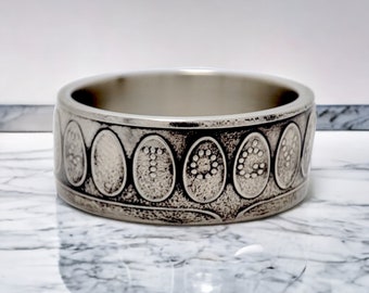 Può includere: Un anello d'argento con un motivo decorativo di forme ovali con piccoli punti all'interno di ogni ovale.