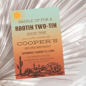 May include: A colorful invitation for a second birthday party with a western theme. The invitation features a sunset background with a sun, cacti, and a cowboy hat. The text reads "Saddle Up for a Rootin Two-Tin Good Time Join us to celebrate Cooper's Second Birthday Saturday | March 22 | 12PM Cooper's House 2 Seashore Ln, Sandwich MA RSVP to Maggie at 11.222.3333"