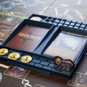 May include: A blue plastic game organiser with compartments for cards and tokens. The organiser has a label that says "Chunk's" and features a star design. There are three yellow counters with the number "1" on them.