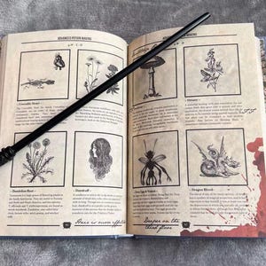 Puede incluir: Un libro abierto con una varita negra encima. El libro se titula "Advanced Potion Making" y tiene ilustraciones de varias plantas y criaturas. El texto en la p&aacute;gina dice "El pelo es m&aacute;s efectivo que las l&aacute;grimas en el tercer piso."