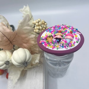 May include: Purple bottle stopper with a white background and colorful sprinkles, ice cream cones, and ice cream scoops.