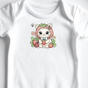 Puede incluir: Body de bebé blanco con un gráfico colorido de un gato con un sombrero de fresa, rodeado de fresas, flores y una mariquita. La ilustración tiene un estilo lindo y caprichoso.