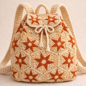 Puede incluir: Una mochila de crochet beige con un patrón repetido de estrellas naranjas. La bolsa tiene correas ajustables, un asa superior y un cierre de cordón con solapa. La mochila está hecha a mano y tiene un aspecto único y texturizado.