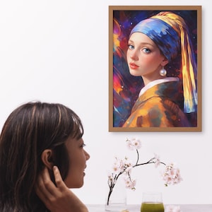 Puede incluir: Una impresión artística enmarcada de una mujer con un pendiente de perla, que lleva un pañuelo azul y amarillo y una túnica amarilla. La obra de arte tiene un fondo abstracto y colorido. El marco es de madera.