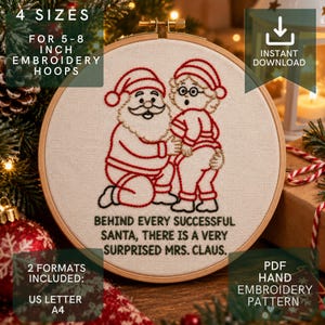 Puede incluir: Un patrón de bordado a mano en un bastidor de madera con una ilustración cosida en rojo y negro de Santa Claus y la Sra. Claus. El texto dice: BEHIND EVERY SUCCESSFUL SANTA, THERE IS A VERY SURPRISED MRS. CLAUS. El diseño está sobre tela color crema.