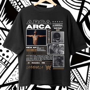 May include: Black t-shirt with a white graphic design featuring the text "ARCA" and a portrait of a man with tattoos. The text "LA MARAVILLA" and "Austin Santos 2024" are also included in the design.
