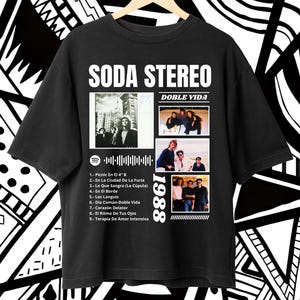 Könnte beinhalten: Schwarzes T-Shirt mit dem Bandnamen "SODA STEREO", Albumcover von "DOBLE VIDA" und dem Jahr "1988". Das Shirt listet auch die Titelliste des Albums auf. Das Design ist in Weiß gedruckt.