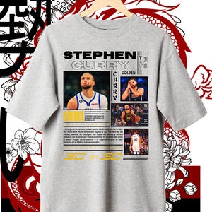 May include: A light gray t-shirt featuring images of Stephen Curry, with the text "STEPHEN CURRY" in black and yellow. The shirt includes text in Spanish and Japanese characters, and is decorated with floral and dragon graphics.
