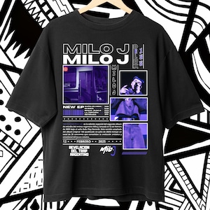 Puede incluir: Camiseta negra con el nombre "MILO J" en blanco y morado, con imágenes y texto relacionados con un álbum musical. El diseño incluye la fecha "12 + FEBRERO + 2025" y la frase "REVELACION DEL TRAP ARGENTINO".
