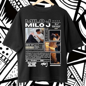 Puede incluir: Camiseta negra con un diseño gráfico blanco que presenta el nombre "Milo J" y una foto de un hombre con una gorra negra y una camisa blanca. El texto "New EP" y una lista de títulos de canciones también se incluyen en el diseño.