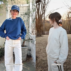 Puede incluir: Dos personas con ropa informal. Una persona lleva una sudadera azul marino, pantalones blancos y una gorra azul. La otra persona lleva una sudadera color crema y un pantal&oacute;n de ch&aacute;ndal. La imagen est&aacute; tomada al aire libre.