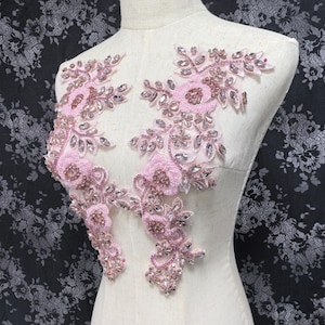 May include: Pink floral applique with crystal embellishments. The applique features delicate flowers and leaves with sparkling rhinestones.