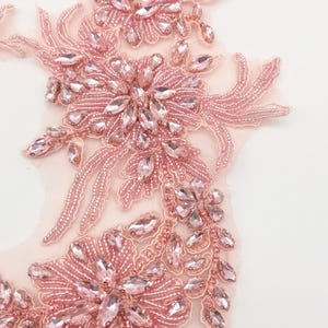 K&ouml;nnte beinhalten: Eine zarte rosa Perlenapplikation mit floralem Design und Kristallverzierungen. Die Applikation ist perfekt, um Kleidung, Accessoires oder Wohnaccessoires einen Hauch von Eleganz zu verleihen.